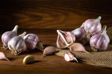Garlic is laid out on a vintage table and burlap before being added to food. Copy space for recipe...