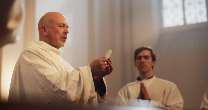 Eucharist Service in Grand Church: Portrait of Christian Minister Holding Communal Bread Leading Holly Communion, Divine Mass or Lord's Supper Ceremony.