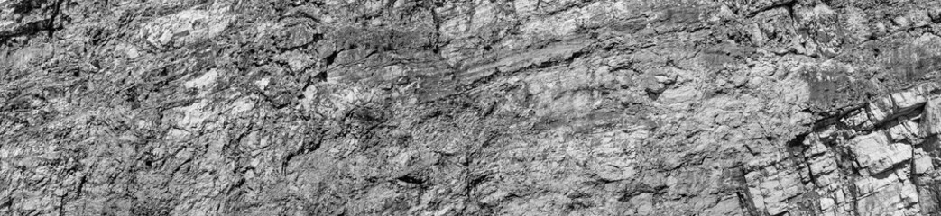 Grungy cragged bumpy pitted cavity stone facade, split layer gap.Ruined cracked shattered worn rough hiking canyon.Old ragged grunge steep marble cliff. Grand vintage crannied damaged impressive gorge