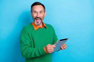 Photo of surprised shock business man wear green jumper hold tablet notepad shocked black friday cheap proposition isolated on blue color background