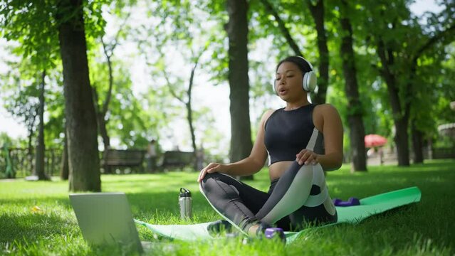African American woman in headphones listening to relaxing music and meditating