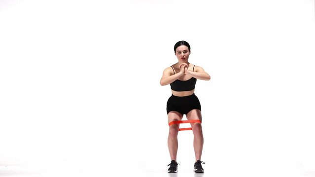 Young sportive girl training with fitness elastic bands over white studio background. Legs exercises. Concept of sport, health, fitness, body care