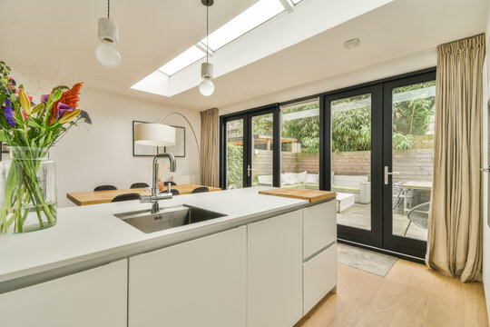 a modern kitchen with white cabinets and an open skylight above the counter area in the room is light wood flooring