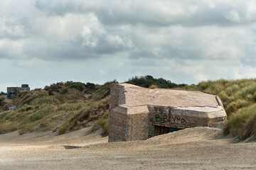 Fototapeta na wymiar blockhaus and marram grass over dunes and storm clouds at Malo-Les-Bains beach in Dunkirk, france