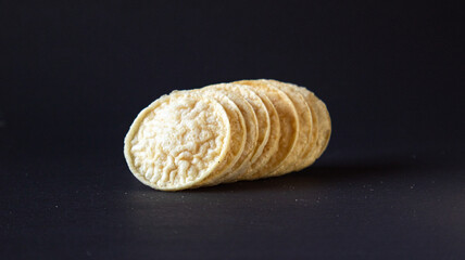 Fototapeta na wymiar Puffed Chips on black background group shot leaning sideways, Healthy gourmet snacks