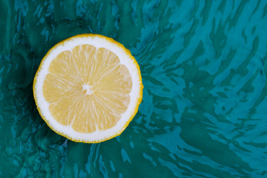 Citrus fruits in green water background with concentric circles and ripples. Refreshing summer concept,
