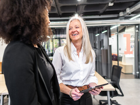 Aged female boss with tablet talking to employee