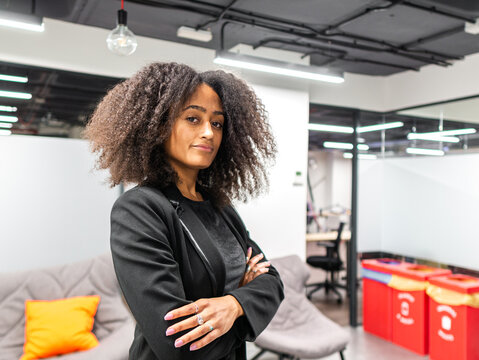 Black young woman standing with crossed arms in office