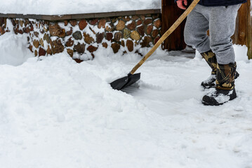 Naklejka premium Human cleaning snow with shovel near house.