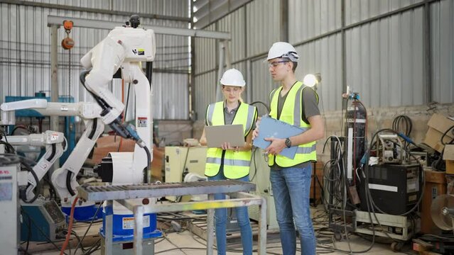 In robotic training instructor teach girl engineer to program robot arm look manual from laptop
