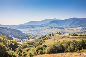 View from a mountain to a valley between mountains with a river and a village on a summer day. View over the hills, mountains, valley, river and village. Carpathians. Ukraine