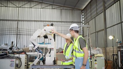 In robotic training instructor teach girl engineer to program robot arm look manual from laptop
