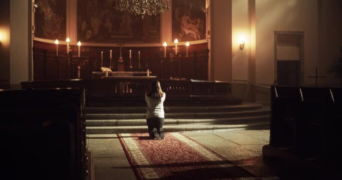 Back View: Christian Woman Getting on her Knees and Starting to Pray in a Church. She Seeks Guidance From her Religious Faith and Spirituality. Spirit of Christianity and Belief in the Goodness of God
