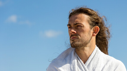 Compassionate man who resembles Christ looking into future in white robe with copy space