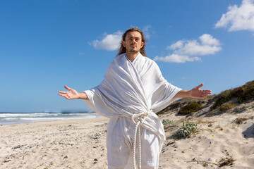 Jesus-like man with open arms on beach