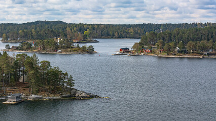 Fototapeta na wymiar Landscape with Scandinavian skerries in the Gulf of Bothnia of the Baltic Sea. A unique natural landscape with rocky islets, overgrown with forest, with neat houses and piers