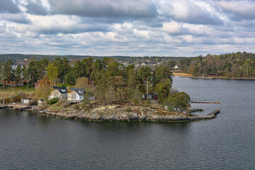 Landscape with Scandinavian skerries in the Gulf of Bothnia of the Baltic Sea. A unique natural landscape with rocky islets, overgrown with forest, with neat houses and piers