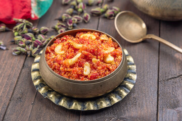 Gajar ka halwa is, Popular Indian dessert pudding made with grated carrots, milk, sugar and nuts served hot with a garnish of almonds, cashew nuts and pistachios.