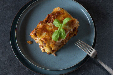 Piece of noodle casserole on a plate isolated on dark background
