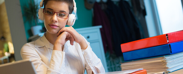 Young businesswoman working from home using headphones and laptop