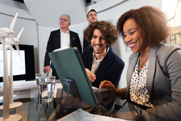 Happy teamwork planning a new project of renewable energy. Multiracial business people using computer working in office.