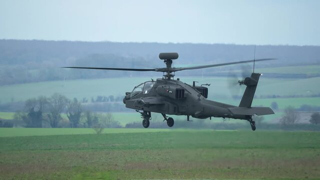 British army Boeing Apache Attack helicopter gunship (AH-64E ZM722 AH64E ArmyAir606) descends to a hover, Wiltshire UK