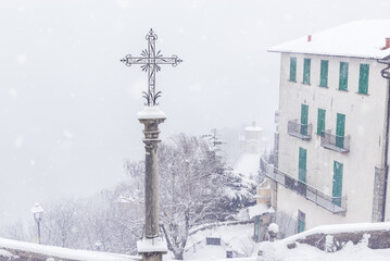 Obraz premium Fog and snowfall at the Sacro Monte di Varese (Santa Maria del Monte), Italy. Winter view downstream with the 14th chapel visible in the haze. World Heritage Site – Unesco