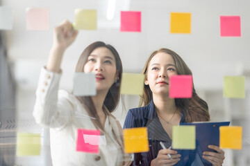 Team of Business female employee with many conflicting priorities arranging sticky notes commenting...