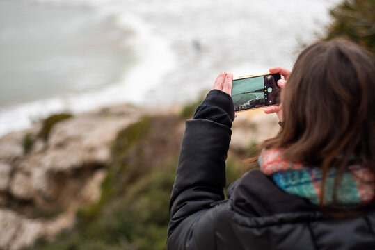 Girl taking a picture of the sea