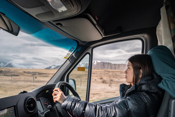 Female traveler drive camper van on empty mountainous road. New Zealand road trip adventure in...