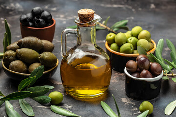 Different types of olives in olive bowls and olive oil on a dark background, Olive concept, banner,...