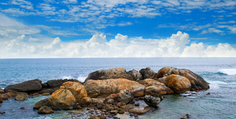 Ocean waves crashing on coastal rocks on a sunny summer day with blue skies.