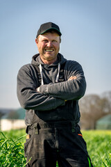 Ein zufriedener Landwird steht auf seinem Acker.