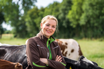  Ausbildungsberuf Landwirtschaft: Hübsche Auszubildende auf einer Weide mit Kühen.