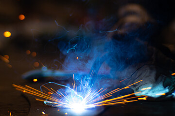 Metal welder works with a steel welder in a factory with protective equipment. Manufacture of metal structures and repair and construction services according to the concept of manual labor.