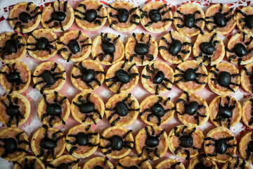 Spider shaped cookies with black olives on a pattern shelf