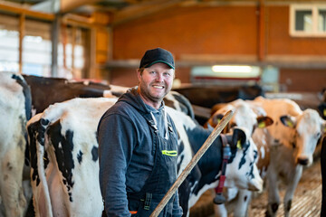  Landwirt bei der Arbeit im Bewegungsbereich eines modernen Milchviehstalles.