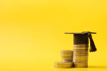 Graduated cap with coins on yellow background. Savings for education concept, back to school...