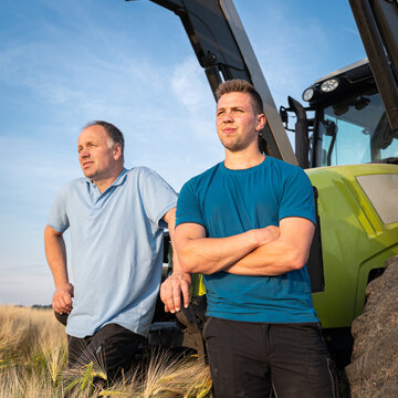 Was bringt die Zukunft, zwei Landwirte diskutieren an einem Trecker, der im reifen Getreidefeld steht.