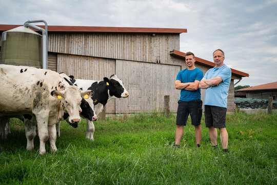 Stolz auf Erreichtes: Landwirt und sein Sohn besprechen sich auf einer Wiese mit Rindern, wie es weiter gehen soll.