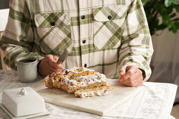 Man in a checkered shirt sitting at the table ready to eat traditional german christmas pastry...