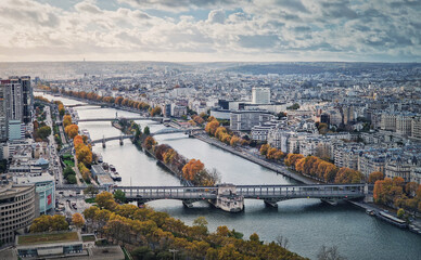 Aerial panorama of Paris city, France. Multiple bridges over the Seine river and vibrant colored autumn trees on the riverbank. Beautiful fall season cityscape panoramic view
