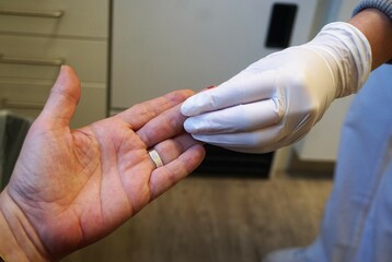Hand von Ärztin mit weißen medizinischen Handschuhen berührt Hand von Patientin in Arztpraxis