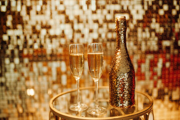 Champagne bottle and glasses against luxury glow golden rain decoration expensive holidays party