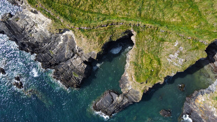 Grassy cliffs on the Atlantic Ocean coast. Landscape of Ireland from a height. Seaside rocks. Aerial photo.