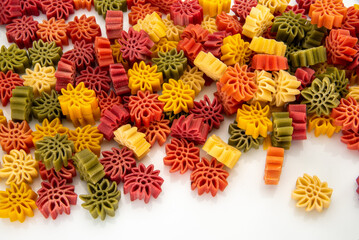 Edelweiss flower shaped egg pasta typical of the Langhe; Italy. Colorful dough pasta with spinach, carrot and beetroot, macaroni isolated on white in top view