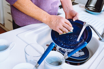 men's hands washing dishes in sink with detergent