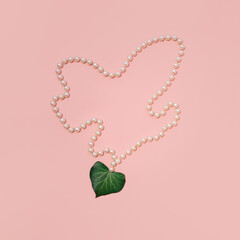 Pearl necklace with fresh green Ivy leaf, heart shaped. Minimal aesthetic love concept. Pastel pink...