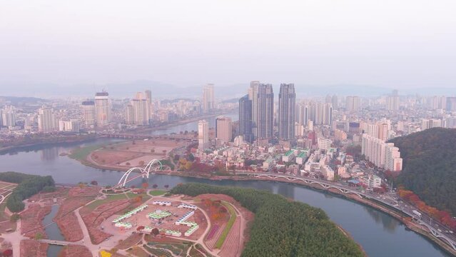Ulsan: Aerial view of city in South Korea, modern high-rise buildings (skyscrapers) at sunset, trees in autumn colors, Taehwagang National Garden - landscape panorama of Eastern Asia from above