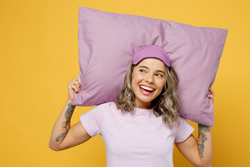 Calm young fun woman she wears purple pyjamas jam sleep eye mask rest relax at home hold pillow...
